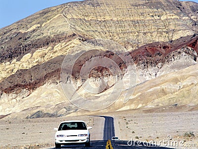 Car at desert road with colored mountains Stock Photo