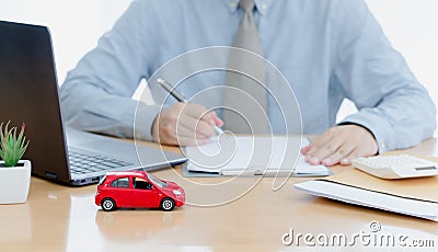 A car on desk envelope with man signing purchase documents in background. while hand complete the insurance policy, rental Stock Photo