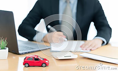 A car on desk envelope with man signing purchase documents in background. while hand complete the insurance policy, rental Stock Photo