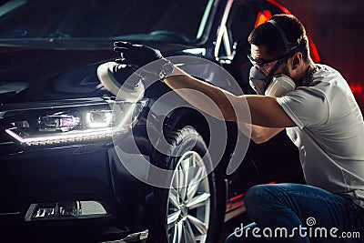 Car detailing - man with orbital polisher in auto repair shop. Selective focus. Stock Photo