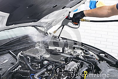 Car detailing. Manual car wash engine with pressure water. Washing car engine with water nozzle. Car washman worker cleaning vehic Stock Photo