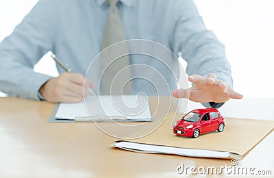 A Car on document envelope with man signing purchase documents in background. while hand complete the insurance policy, rental Stock Photo