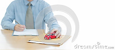 A Car on document envelope with man signing purchase documents in background. while hand complete the insurance policy, rental Stock Photo