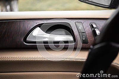 Car door handle with door lock control panel inside luxury car interior with leather Stock Photo