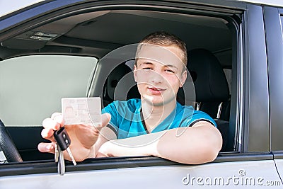 Car driver. Caucasian teen boy showing driver license, new car k Stock Photo