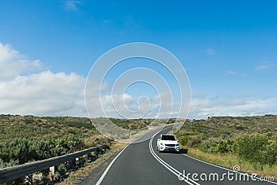 Car driving along curving coastal road on sunny day Stock Photo