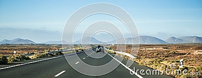 Car driving away to mountains in Canary Island desert Stock Photo