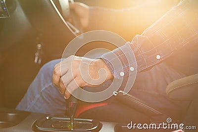 Car driving concept : Driver hand on automatic gear inside the modern car. Car interior with morning golden sun light flare effect Stock Photo