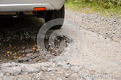 Car driving through huge deep pothole in road Stock Photo
