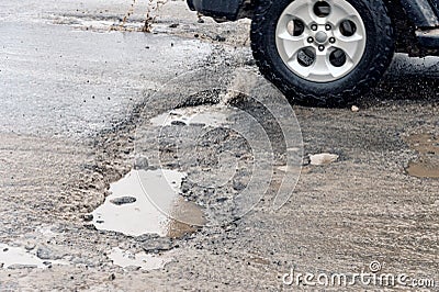 Car driving through a pothole with splashes of water Stock Photo