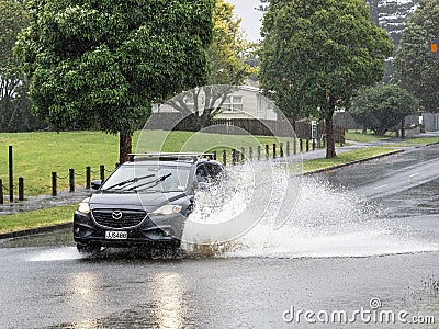 Car driving through puddle. Heavy rain. Auckland, New Zealand - January 27, 2023 Editorial Stock Photo