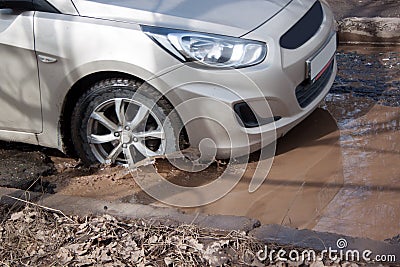 Car is driving through a big pothole filled with water. Dangerous destroyed roadbed. Stock Photo