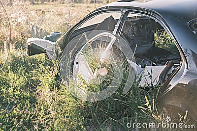 Car dump, scrap metal. Close-up of an old abandoned car in a junkyard with grass sprouting inside and overgrown cobwebs Stock Photo