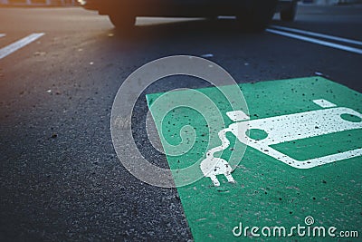 car entering a parking lot with symbol of a car with cable plug painted in green and white on ground. Stock Photo