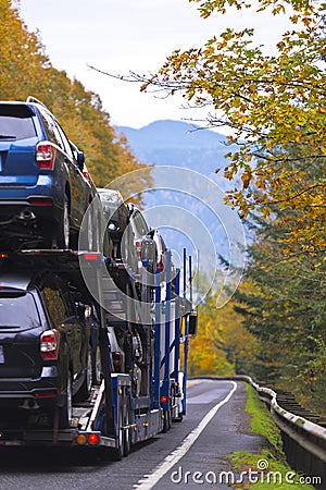 Car hauler semi truck transporting cars on spectacular autumn hi Stock Photo