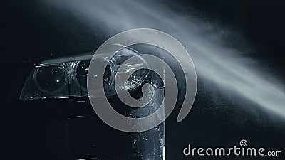 Car headlight wash. Washing modern vehicle body by high pressure jet wash hose water. Auto glass headlamp, angel eyes in Stock Photo