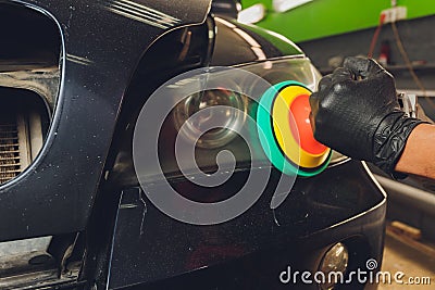 Car headlights cleaning with power buffer machine at car service. Stock Photo
