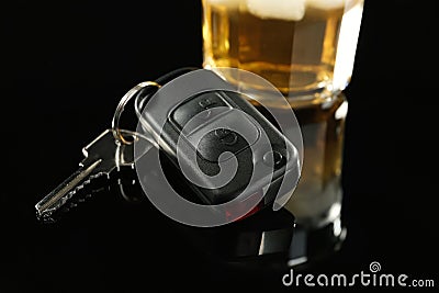 Car key near glass of alcohol on black table, closeup. Dangerous drinking and driving Stock Photo
