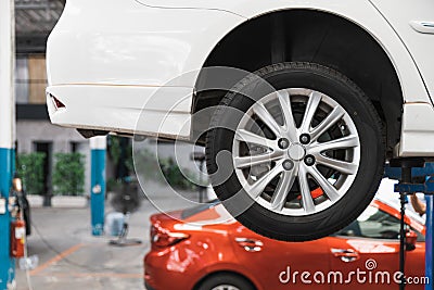 Car on the lift at the car service that waiting to inspect by mechanic. Focus on right rear wheel. Auto repair shop. Stock Photo