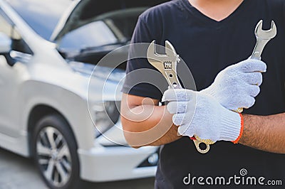 Car machanic holding wrench near car. Car maintenance concept Stock Photo