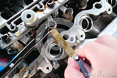Car mechanic checking and adjusting valves of car engine with feeler gauge or thickness gauge tool Stock Photo