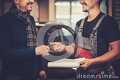 Car mechanic giving client keys to his repaired car in auto repair service. Stock Photo