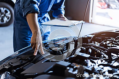 Car mechanic holding clipboard and checking to maintenance vehicle by customer claim order in auto repair shop garage. Engine Stock Photo