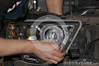 The mechanic installs the BI-LED lens in the headlight housing. Stock Photo