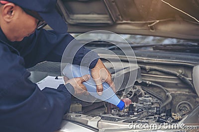 Car Mechanic man hands pouring Deionized purified Distilled water for car battery mechanical service. Close up hands man hold Stock Photo