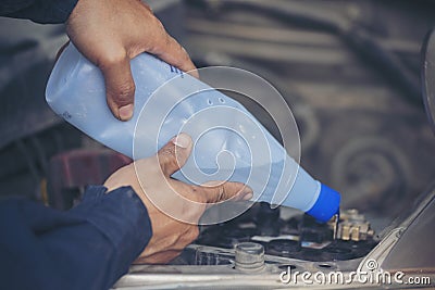 Car Mechanic man hands pouring Deionized purified Distilled water for car battery mechanical service. Close up hands man hold Stock Photo