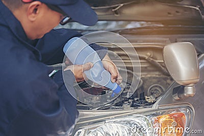 Car Mechanic man hands pouring Deionized purified Distilled water for car battery mechanical service. Close up hands man hold Stock Photo