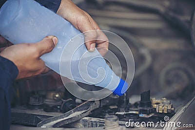 Car Mechanic man hands pouring Deionized purified Distilled water for car battery mechanical service. Close up hands man hold Stock Photo