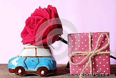 A car model carrying jumbo beautiful red rose and gift box, delivering love. Happy Valentine& x27;s day concept Stock Photo