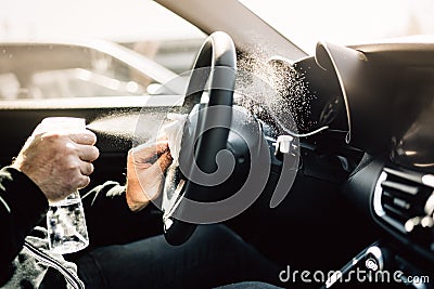 Car owner disinfecting vehicle with alcohol based sanitizing solution spray.Touched surfaces sanitation.Coronavirus COVID-19 Stock Photo