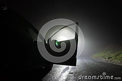 A car parked, with door open, on the side of the road, underneath a street light. On a foggy winters night Stock Photo