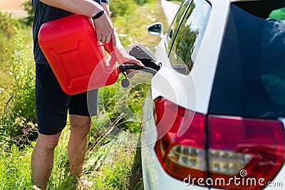 The car parked on the side of the road, the driver refuels the car from the canister. Help on the road. Lack of fuel - oil, diesel Stock Photo