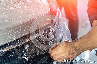 Car protection film or PPF process of wrapping and installing on car hood by detailer worker hands, close up Stock Photo