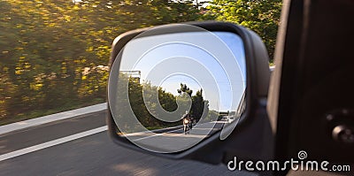 Car rear view mirror with the image of a biker approaching to overtake Stock Photo