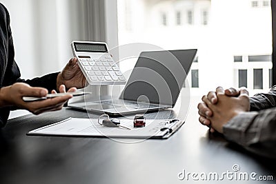 A car rental company employee holds a white calculator to show the tenant the rental price. Stock Photo