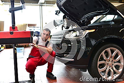 Car repair shop - worker checks and adjusts the headlights of a Stock Photo