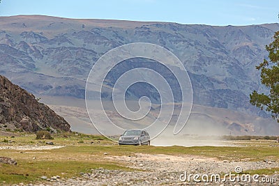 The car rides on the steppes of Mongolia. A lot of dust, mountains in the background Stock Photo
