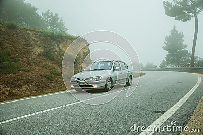 Car in a road passing through wooden landscape with mist Editorial Stock Photo