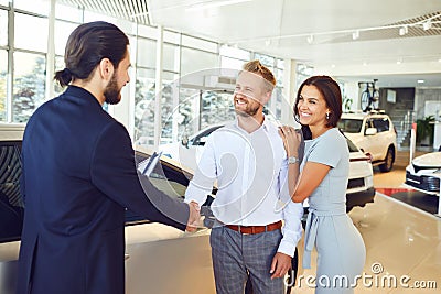 A car salesman and a buyer shake hands. A couple buys a car Stock Photo
