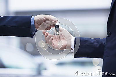 Car salesman handing over the keys for a new car to a young businessman, close-up Stock Photo