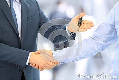 Car salesman handing over the keys for a new car to a young businessman . Handshake between two business people. Focus on a key Stock Photo