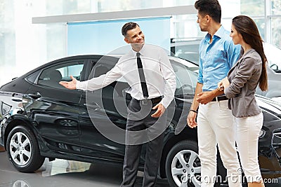 Car Salesman Invites Customers at Showroom. Stock Photo