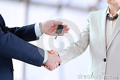 Car saleswoman handing over the keys for a new car to a young business people Stock Photo