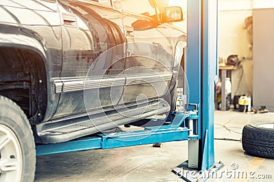 Car service center. Old rusty offroad SUV vehicle raised on lift at maintenance station. Automobile repair and check up. Stock Photo