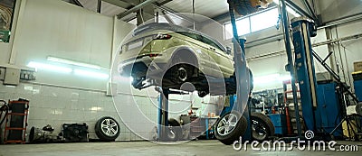 Car service center. Vehicle raised on lift at maintenance station. Auomobile repair and check up. Stock Photo