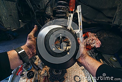 Car service from the first person mechanic. Male hands. Repair of the front wheel hub, replacement of Brake disc and pads, Stock Photo